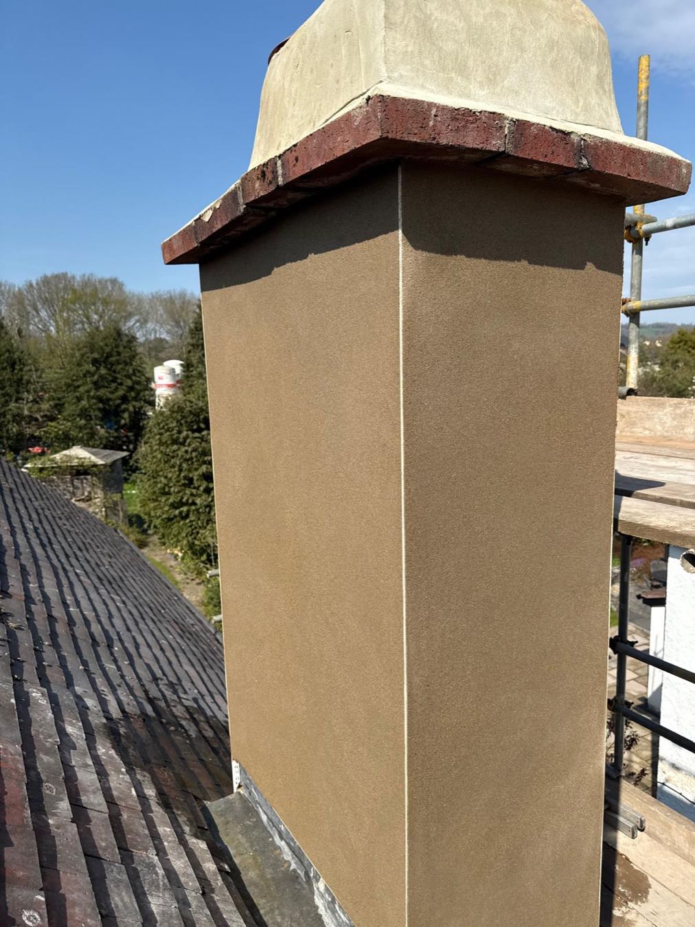 A freshly rendered chimney stack cut in cleanly beneath the original brick oversail