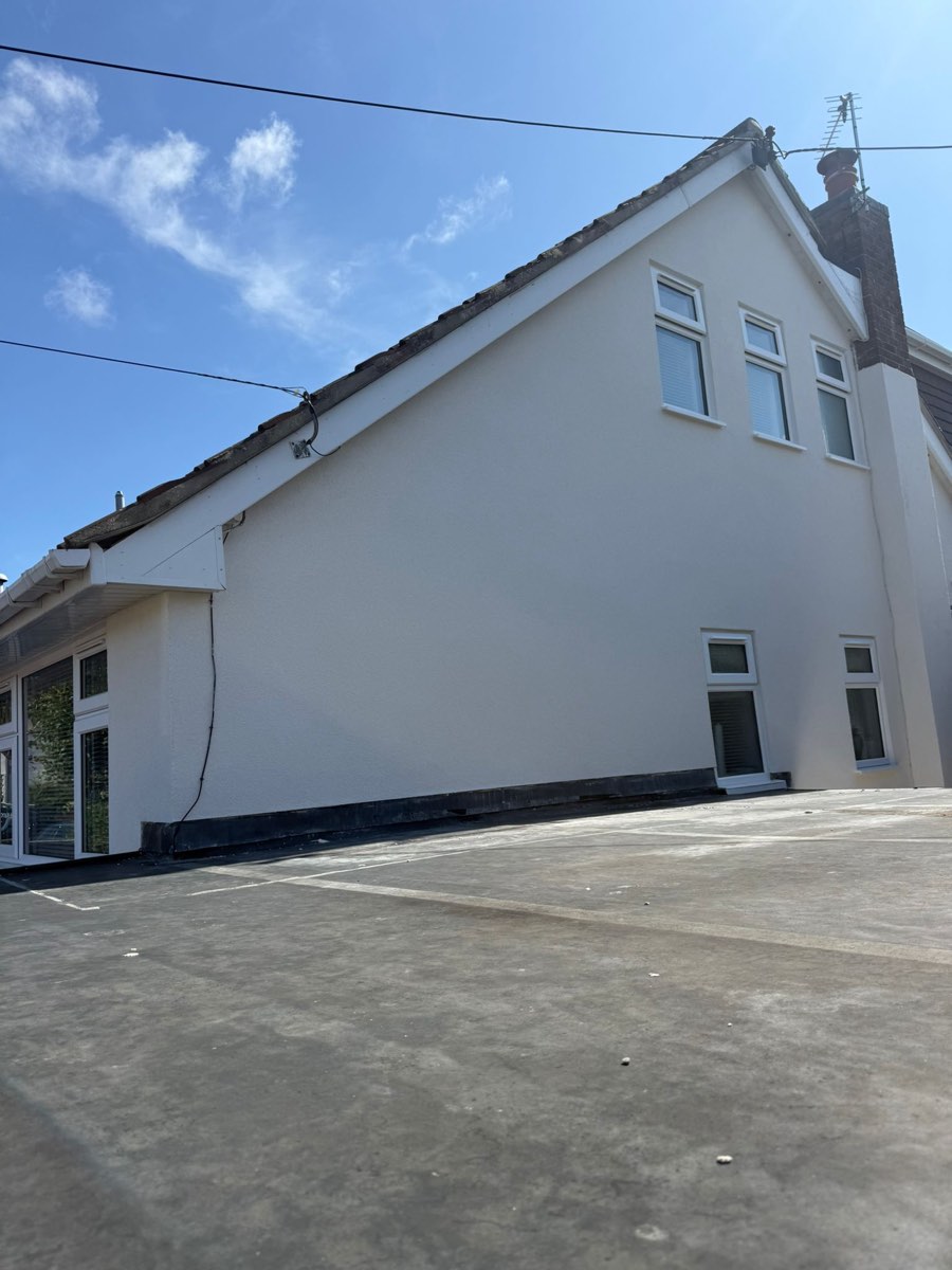 The same gable end finished in clean white render with a dark plinth along the base