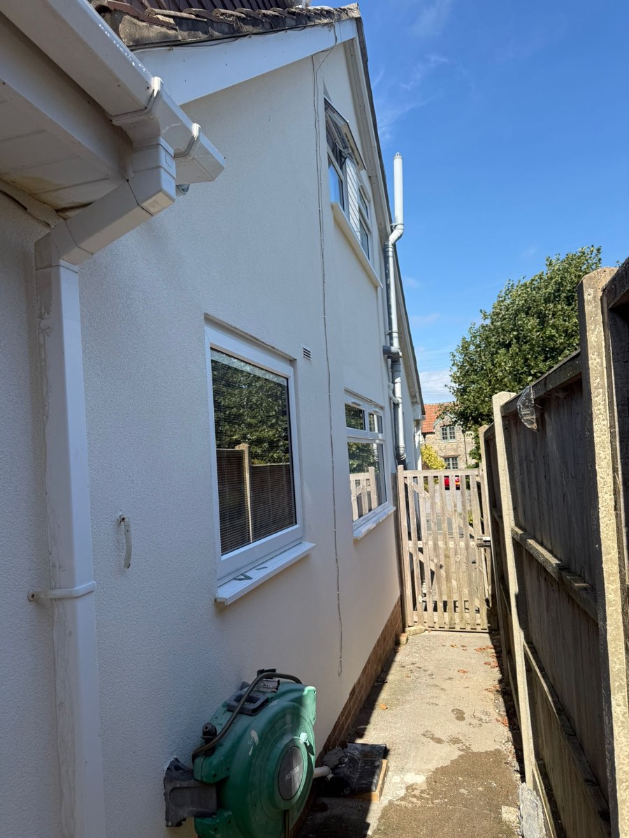The same side passage after rendering, smooth white walls running down to a timber gate