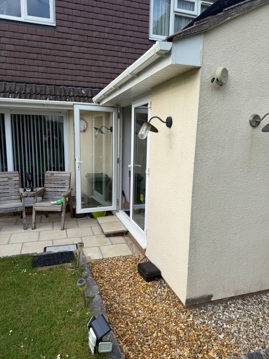 Rendered wall beside patio doors, meeting a gravel border and lawn