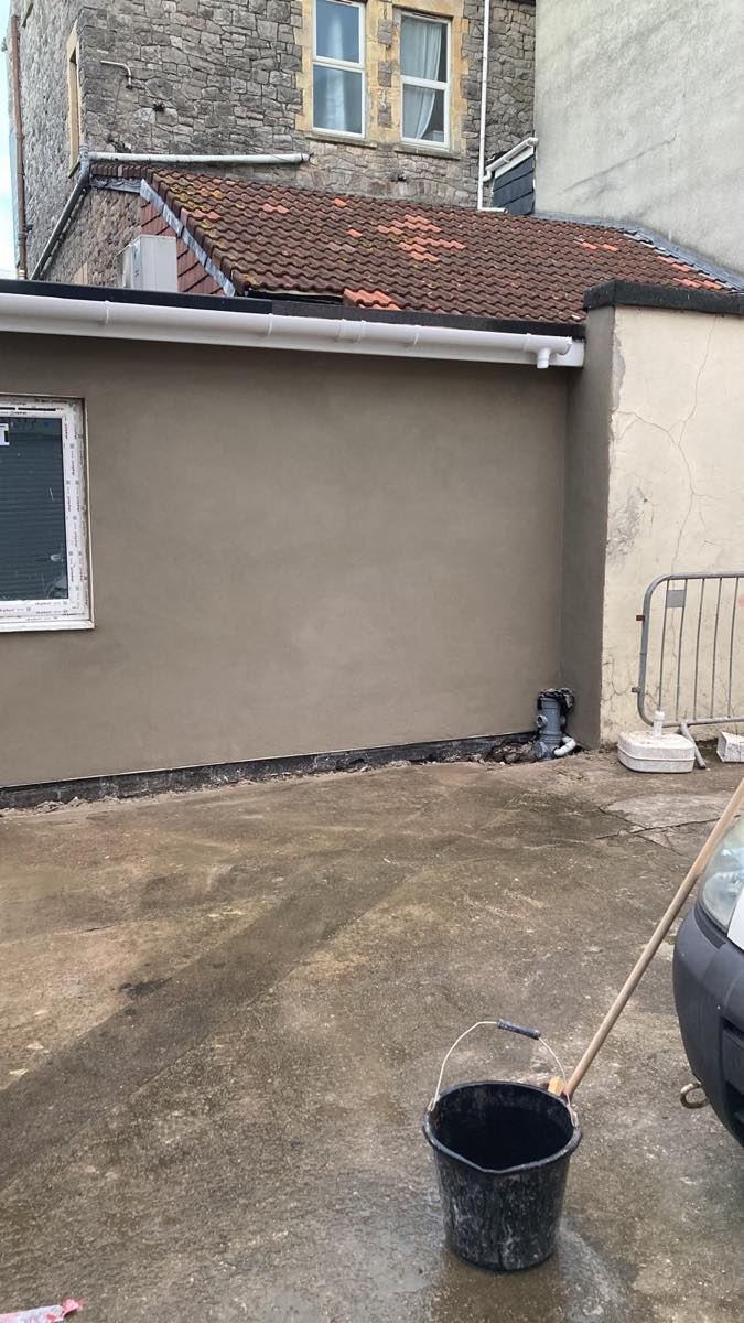 A finished render corner, flat and even, running straight up to an older wall