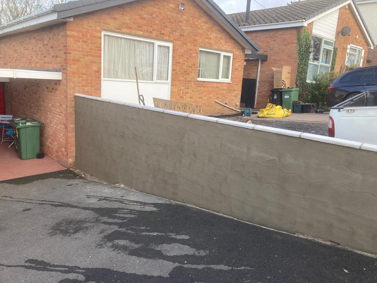 A front boundary wall fully rendered with an even combed finish and coping stones set level