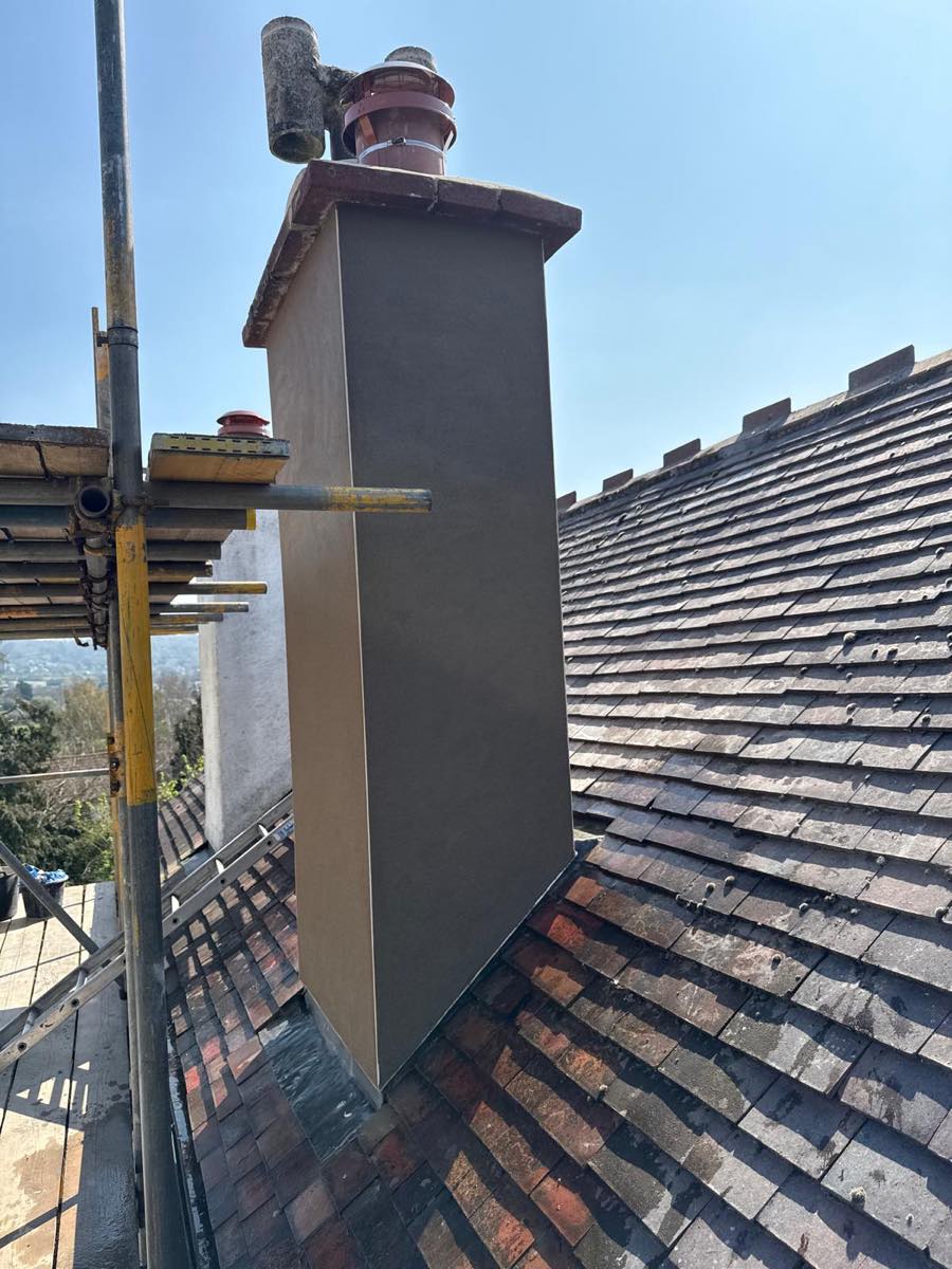 A rendered chimney dressed neatly down to the lead flashing with a roof valley behind